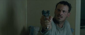 Movie still from “The Rover” (2014), directed by David Michôd – A man is holding a gun in his hand; Close Up shot, Over the shoulder angle