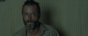 Movie still from “The Rover” (2014), directed by David Michôd – A person with a beard; Close Up shot, Over the shoulder angle