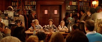 Movie still from “The Royal Tenenbaums” (2001), directed by Wes Anderson – A group of people sitting at a table with candles in front of them; Medium shot, High angle