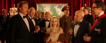 Movie still from “The Royal Tenenbaums” (2001), directed by Wes Anderson – A group of people standing in front of a painting holding drinks; Medium shot, Low angle