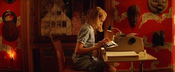 Movie still from “The Royal Tenenbaums” (2001), directed by Wes Anderson – A woman is sitting at a desk and playing an electronic keyboard; Medium shot, High angle