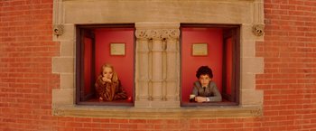Movie still from “The Royal Tenenbaums” (2001), directed by Wes Anderson – A woman and a man sitting on a window ledge; Wide shot, Overhead angle