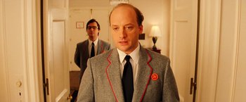 Movie still from “The Royal Tenenbaums” (2001), directed by Wes Anderson – A man in a suit and tie standing next to another man in a suit and tie; Close Up shot, Over the shoulder angle