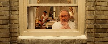 Movie still from “The Royal Tenenbaums” (2001), directed by Wes Anderson – An older man looking out of a window at a young woman; Medium shot, Over the shoulder angle