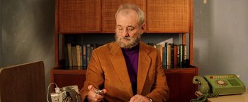 Movie still from “The Royal Tenenbaums” (2001), directed by Wes Anderson – An older man in a brown jacket is holding a cell phone; Medium shot, Low angle