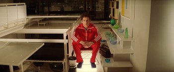 Movie still from “The Royal Tenenbaums” (2001), directed by Wes Anderson – A man sitting on a chair in a room; Medium shot, Low angle