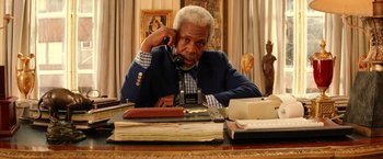 Movie still from “The Royal Tenenbaums” (2001), directed by Wes Anderson – An older man sitting at a desk talking on the phone; Medium shot, Low angle