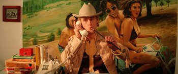 Movie still from “The Royal Tenenbaums” (2001), directed by Wes Anderson – A man in a cowboy hat is holding a phone; Medium shot, Low angle