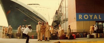 Movie still from “The Royal Tenenbaums” (2001), directed by Wes Anderson – A group of men standing next to each other near a boat; Wide shot, Low angle