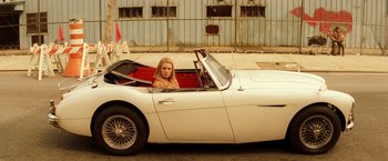 Movie still from “The Royal Tenenbaums” (2001), directed by Wes Anderson – A woman sitting in the driver's seat of a white sports car; Wide shot, High angle