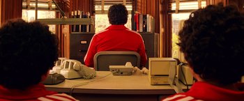 Movie still from “The Royal Tenenbaums” (2001), directed by Wes Anderson – A man sitting at a desk in front of a computer; Medium shot, Over the shoulder angle