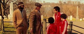 Movie still from “The Royal Tenenbaums” (2001), directed by Wes Anderson – A group of people standing next to each other near a body of water; Medium shot, Over the shoulder angle