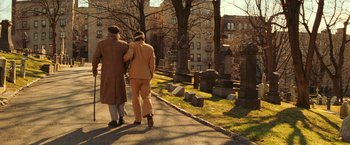 Movie still from “The Royal Tenenbaums” (2001), directed by Wes Anderson – Two people walking down a path near a cemetery; Wide shot, High angle