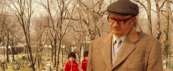 Movie still from “The Royal Tenenbaums” (2001), directed by Wes Anderson – An old man wearing a hat and a suit; Close Up shot, Over the shoulder angle