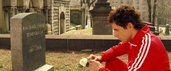 Movie still from “The Royal Tenenbaums” (2001), directed by Wes Anderson – A woman in a red shirt is holding a white flower; Medium shot, Over the shoulder angle
