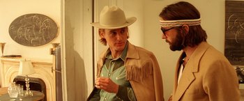 Movie still from “The Royal Tenenbaums” (2001), directed by Wes Anderson – A man wearing a cowboy hat talking to another man in front of a mirror; Medium shot, Over the shoulder angle