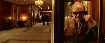 Movie still from “The Royal Tenenbaums” (2001), directed by Wes Anderson – An older man sitting in front of a mirror in a hotel hallway; Medium shot, Over the shoulder angle