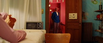 Movie still from “The Royal Tenenbaums” (2001), directed by Wes Anderson – A man standing in a doorway of a room; Wide shot, Over the shoulder angle