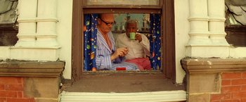 Movie still from “The Royal Tenenbaums” (2001), directed by Wes Anderson – Two men sitting on a window sill drinking coffee; Medium shot, Low angle
