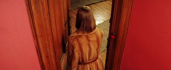 Movie still from “The Royal Tenenbaums” (2001), directed by Wes Anderson – A woman in a fur coat standing in a doorway; Medium shot, High angle