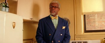 Movie still from “The Royal Tenenbaums” (2001), directed by Wes Anderson – An older man wearing a suit and a bow tie; Medium shot, Low angle