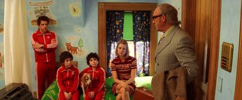Movie still from “The Royal Tenenbaums” (2001), directed by Wes Anderson – A group of people sitting in a room with a dog; Medium shot, Over the shoulder angle