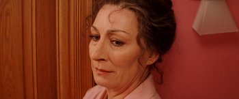 Movie still from “The Royal Tenenbaums” (2001), directed by Wes Anderson – A woman's face in a pink shirt; Close Up shot, High angle