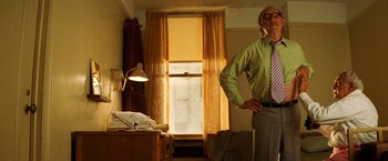 Movie still from “The Royal Tenenbaums” (2001), directed by Wes Anderson – An older man standing in a room with a window; Medium shot, Low angle