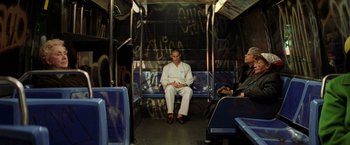 Movie still from “The Royal Tenenbaums” (2001), directed by Wes Anderson – A man sitting on a bus with graffiti all over it; Wide shot, Low angle