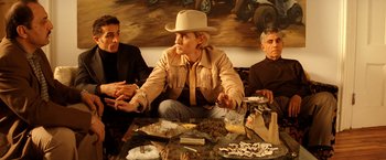 Movie still from “The Royal Tenenbaums” (2001), directed by Wes Anderson – A group of people sitting around a table with food on top of it; Medium shot, Low angle
