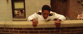 Movie still from “The Royal Tenenbaums” (2001), directed by Wes Anderson – A man in a uniform leaning on a brick wall; Medium shot, Low angle