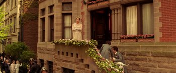 Movie still from “The Royal Tenenbaums” (2001), directed by Wes Anderson – A woman standing on a balcony next to two men; Wide shot, Over the shoulder angle