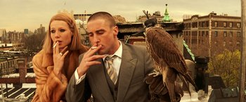 Movie still from “The Royal Tenenbaums” (2001), directed by Wes Anderson – A man in a business suit smoking a cigarette while standing next to two birds; Close Up shot, Low angle