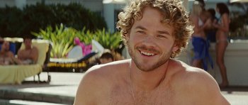 Movie still from “The Ruins” (2008), directed by Carter Smith – A person with curly hair smiling; Close Up shot, Over the shoulder angle