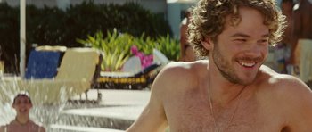 Movie still from “The Ruins” (2008), directed by Carter Smith – A man with curly hair is sitting in a swimming pool; Close Up shot, Over the shoulder angle