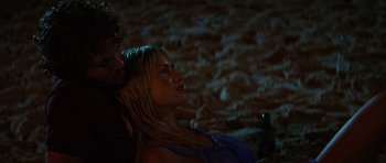 Movie still from “The Ruins” (2008), directed by Carter Smith – A woman sitting next to a man holding a bottle; Close Up shot, High angle