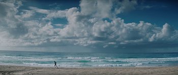 Movie still from “The Ruins” (2008), directed by Carter Smith – A person running on the beach near the ocean; Extreme Wide shot, Low angle