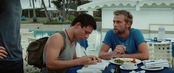 Movie still from “The Ruins” (2008), directed by Carter Smith – Two young men sitting at a table writing on a piece of paper; Medium shot, Over the shoulder angle