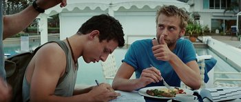 Movie still from “The Ruins” (2008), directed by Carter Smith – Two young men sitting at a table with a plate of food; Close Up shot, Over the shoulder angle