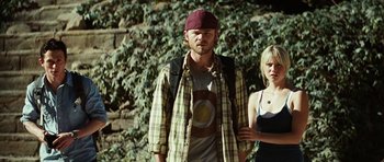 Movie still from “The Ruins” (2008), directed by Carter Smith – A man and a woman standing next to each other in front of a bush; Medium shot, Low angle