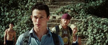 Movie still from “The Ruins” (2008), directed by Carter Smith – A group of people standing next to each other on some steps; Close Up shot, Low angle