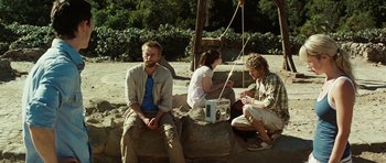 Movie still from “The Ruins” (2008), directed by Carter Smith – A group of people sitting on a rock; Wide shot, Over the shoulder angle