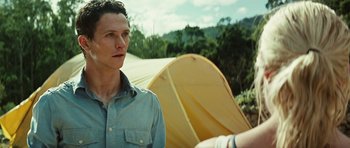 Movie still from “The Ruins” (2008), directed by Carter Smith – A man standing in front of a yellow tent; Close Up shot, Over the shoulder angle