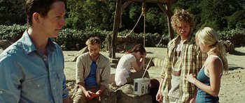 Movie still from “The Ruins” (2008), directed by Carter Smith – A man and a woman sitting next to each other on rocks; Medium shot, Over the shoulder angle