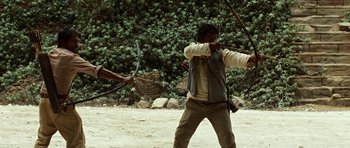 A man holding a bow and arrow in front of a basket