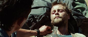 Movie still from “The Ruins” (2008), directed by Carter Smith – A man is holding a glass bottle while another man is holding a knife; Close Up shot, Over the shoulder angle