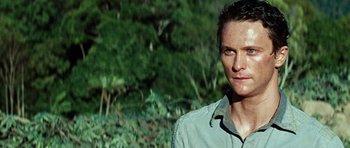 Movie still from “The Ruins” (2008), directed by Carter Smith – A person wearing a shirt near a forest; Close Up shot, Low angle