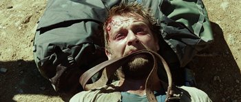 Movie still from “The Ruins” (2008), directed by Carter Smith – A man with a beard and a leather belt around his mouth; Close Up shot, High angle