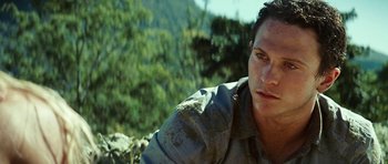 Movie still from “The Ruins” (2008), directed by Carter Smith – A person wearing a shirt near a forest; Close Up shot, High angle