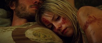 Movie still from “The Ruins” (2008), directed by Carter Smith – A young girl is laying on the ground next to an older man; Close Up shot, Overhead angle